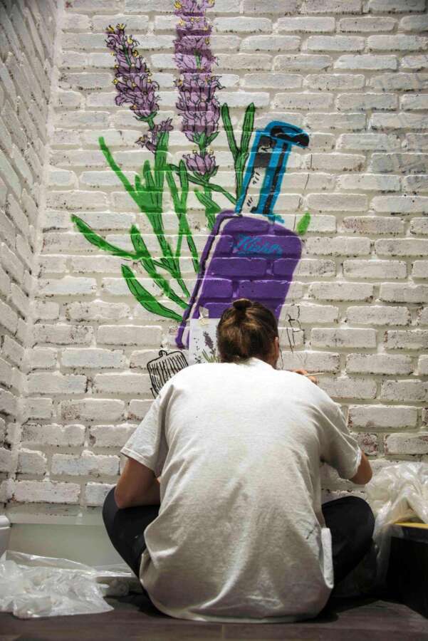 Artist hand painting botanical wall graphics during installation at the Kiehl’s Regent Street flagship store