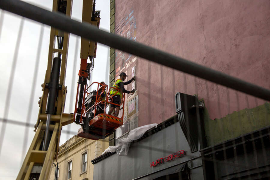 Artist painting the Michelin mural on Portobello Road using a cherry picker lift