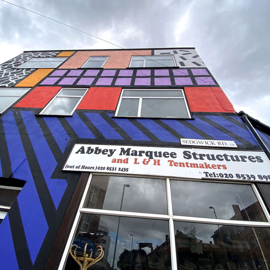 Upward architectural view of Camille Walala Walala Parade mural covering building facade in Leyton London