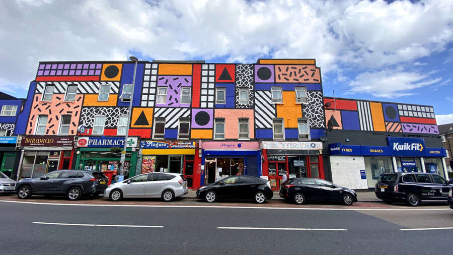 Full street view of Walala Parade mural by Camille Walala across shopfronts on Leyton High Road