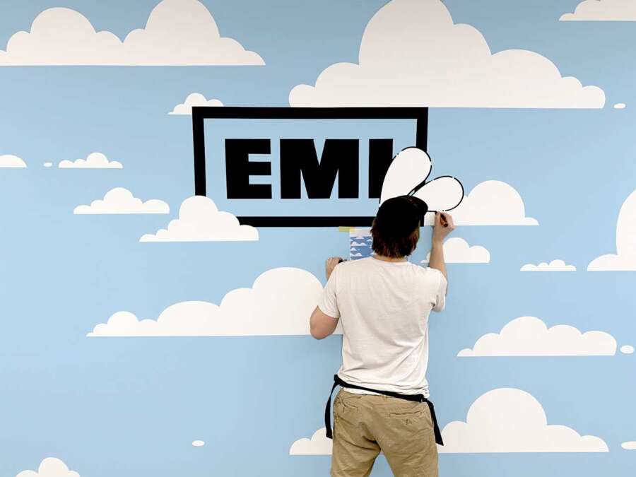 Artist installing EMI logo detail on interior office mural wall