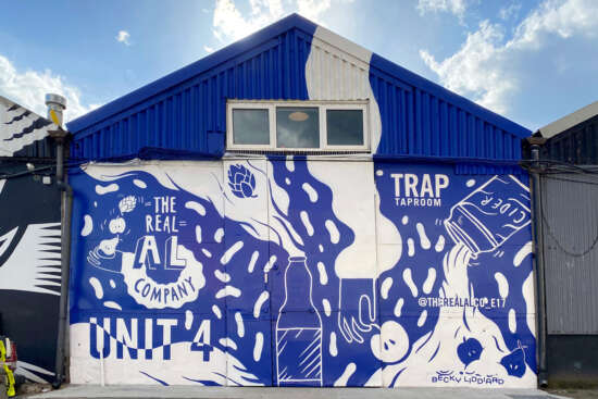 Large-scale hand-painted mural by Becky Liddiard on The Real Al Co building in Walthamstow London produced by Absolutely Studio