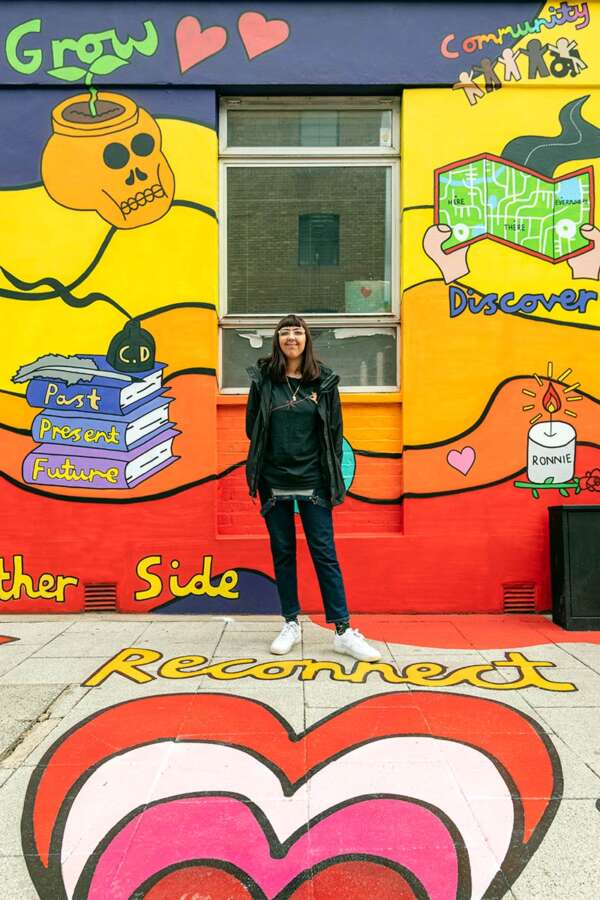 Artist Hannah Hill standing beside her public art mural in Bankside London