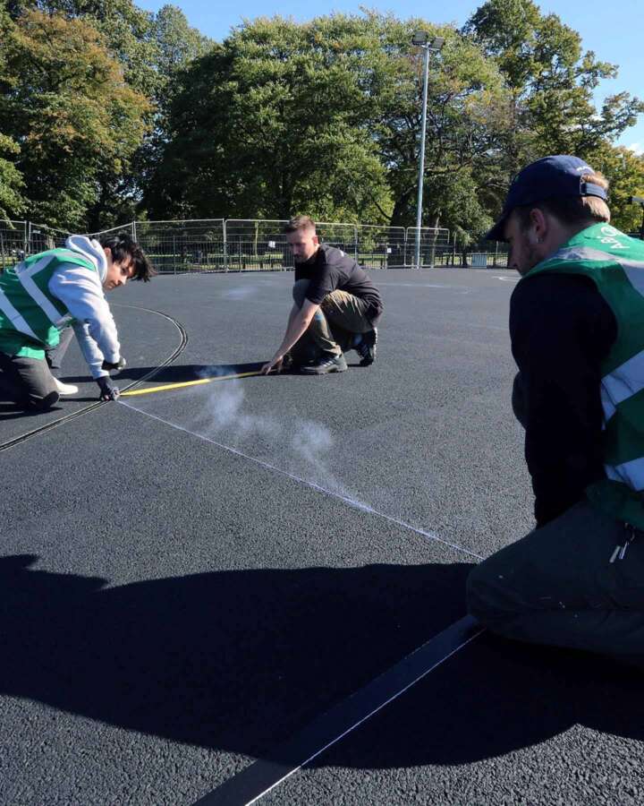 Marking out painted basketball court artwork during installation by Absolutely Studio