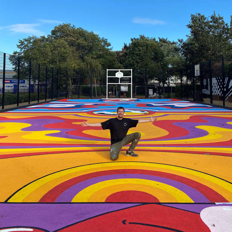 Wide view of completed painted basketball court mural at Orchard Park community sports court