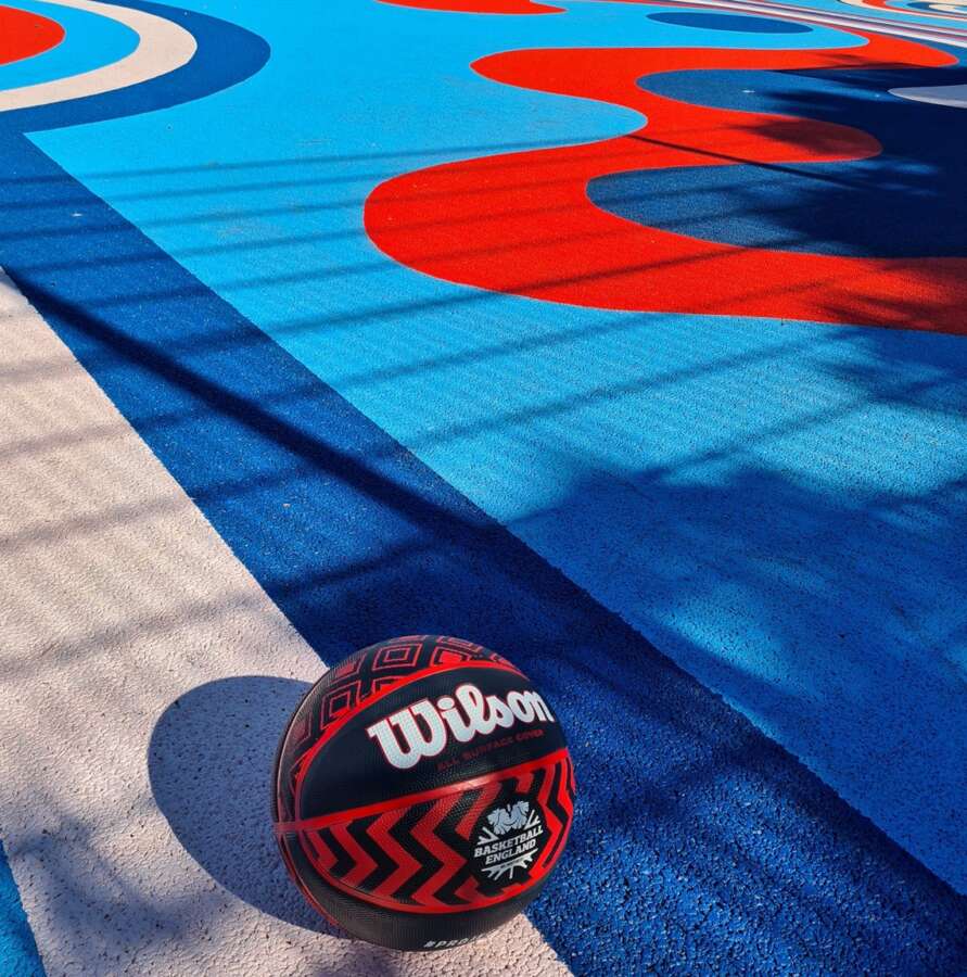 Basketball resting on painted outdoor basketball court mural surface at Orchard Park