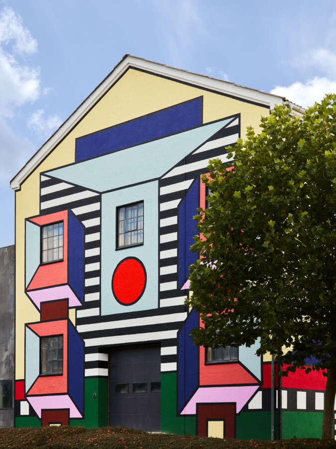 Front façade of Montana Furniture factory with colourful Camille Walala building wrap
