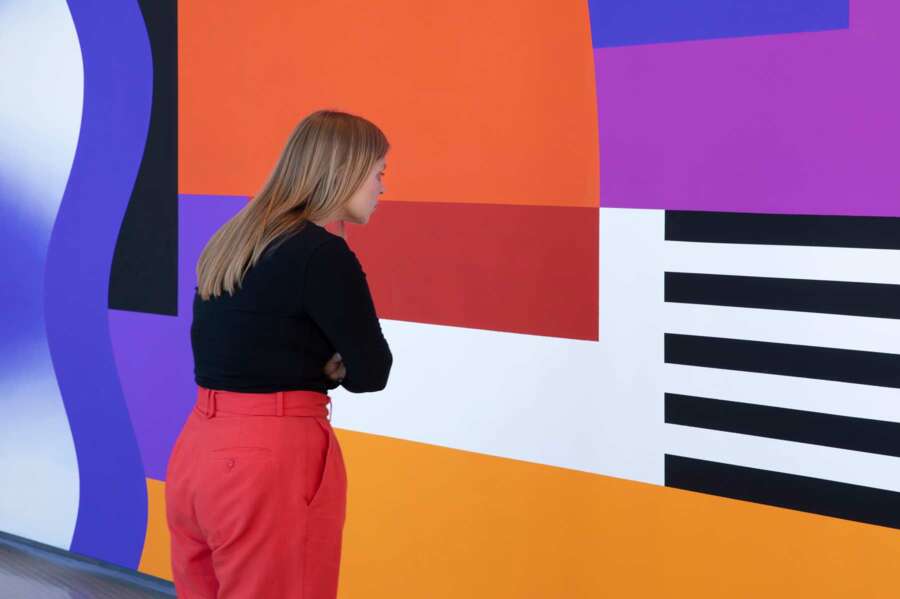 Visitor viewing colourful geometric wall artwork from Camille Walala installation at The Lowry