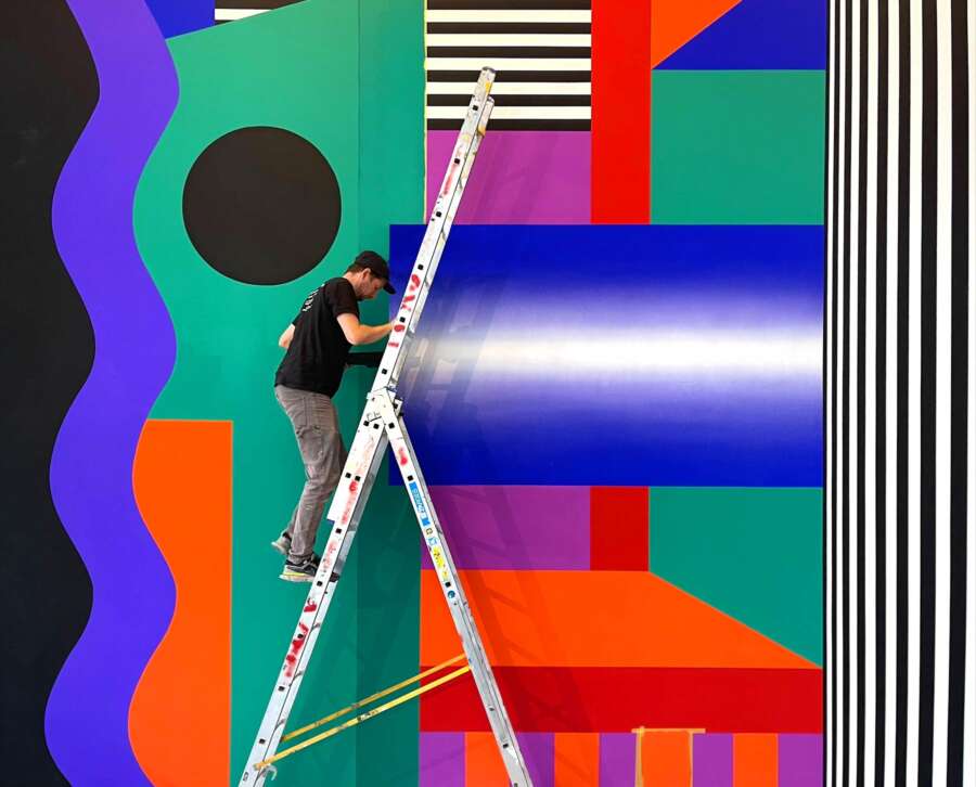 Artist painting Camille Walala wall installation at The Lowry during installation process