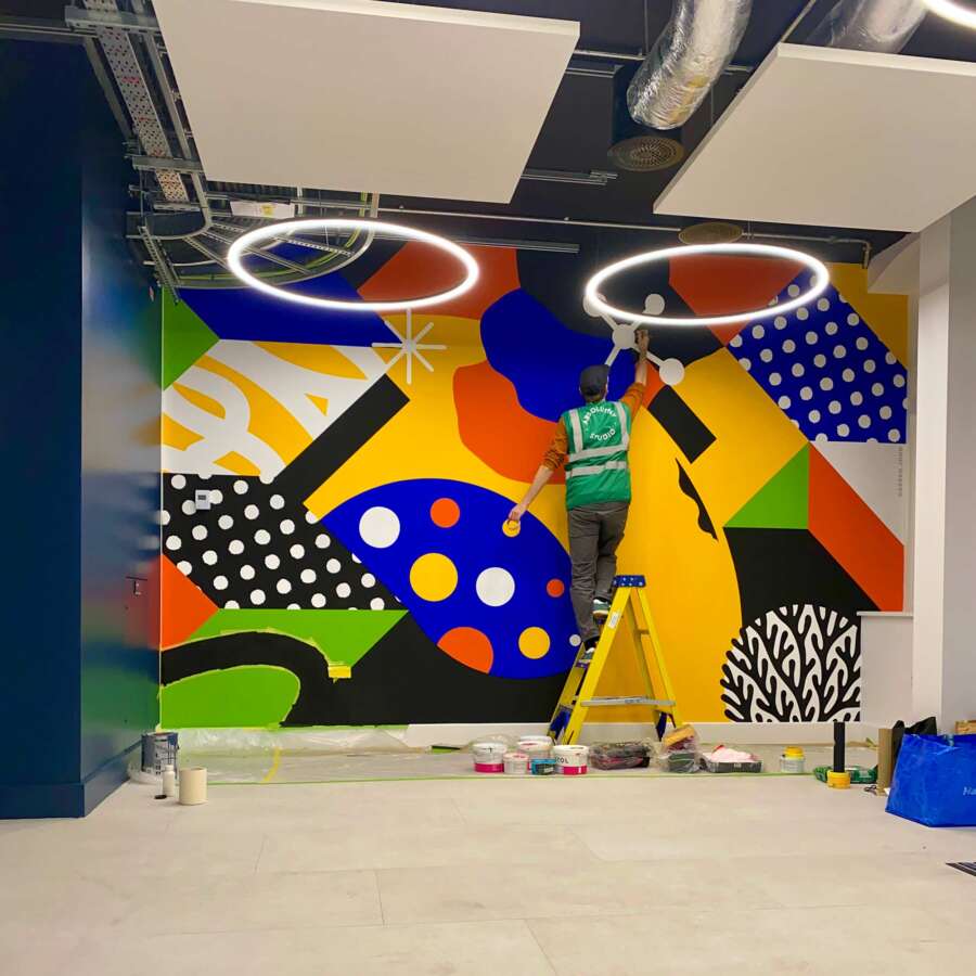 Darren John painting a large abstract mural at the London School of Hygiene & Tropical Medicine