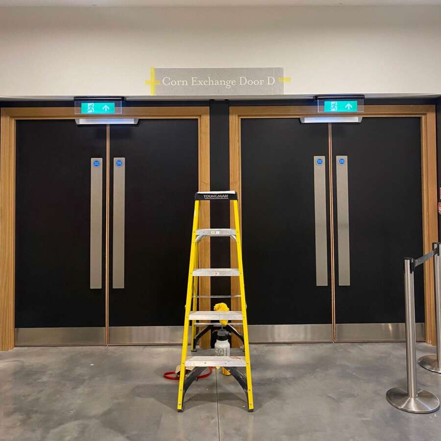 Work in progress signage installation with vinyl guide applied above Corn Exchange doors at Brighton Dome