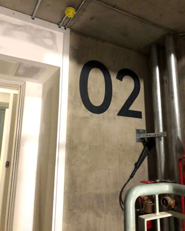 Painted floor number 02 wayfinding signage installed on concrete wall within Lewisham Exchange stair core