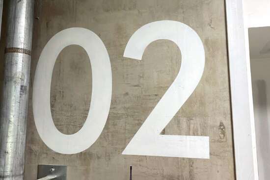 Large hand painted floor level indicator 02 applied directly to exposed concrete wall in fire escape stairwell