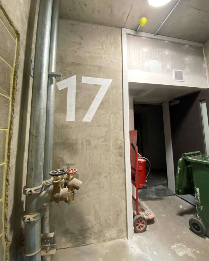 Hand painted wayfinding number 17 installed on concrete stairwell wall during construction phase