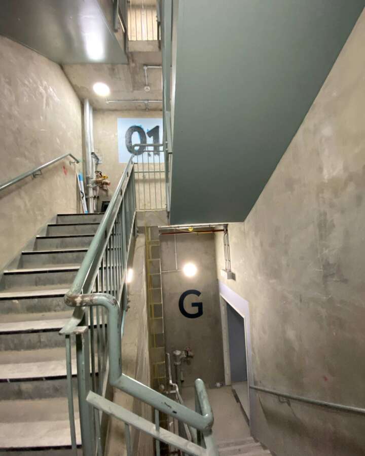 Hand painted wayfinding letter G installed directly onto concrete stairwell wall at Vita Student Lewisham Exchange
