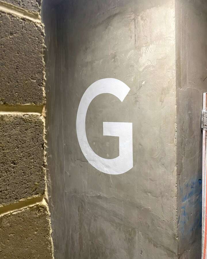 Painted ground level indicator letter G on exposed concrete stairwell wall