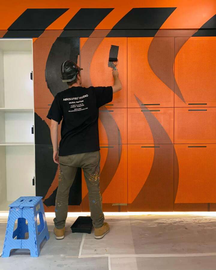 Artist installing mural artwork inside Nike headquarters in Kings Cross London