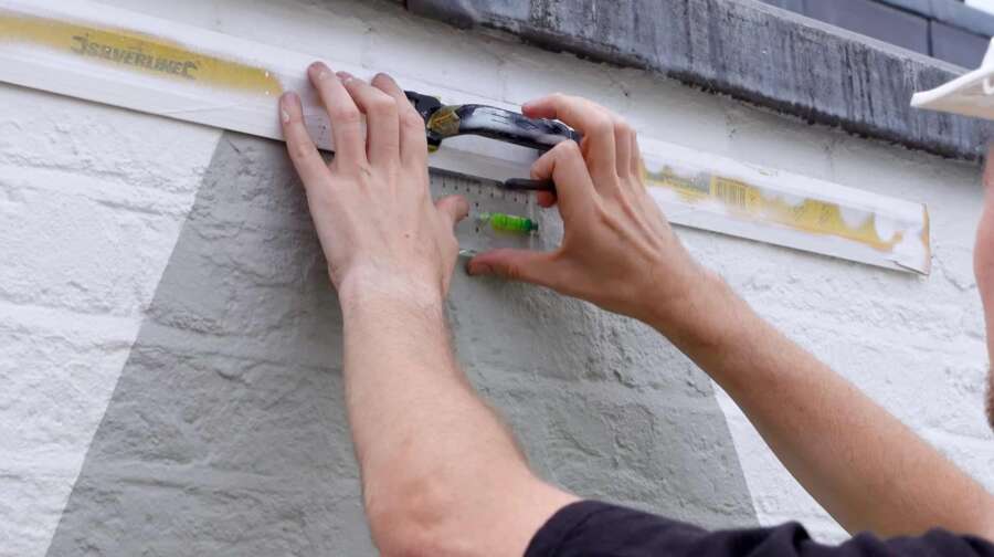 Applying hand painted architectural lettering to brick parapet during Magnetos signage restoration